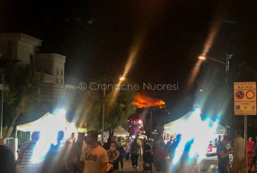 Turisti a Budoni e, sullo sfondo, l'incendio (foto Mary Cabboi)