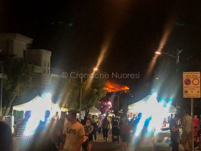 Turisti a Budoni e, sullo sfondo, l'incendio (foto Mary Cabboi)